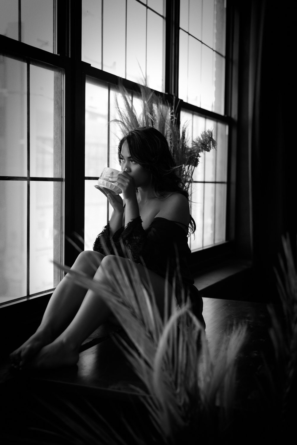 woman sipping from a cup at window in lingerie